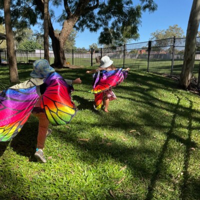 Pre-Kindy children running with butterfly wings in the Jacaranda yard